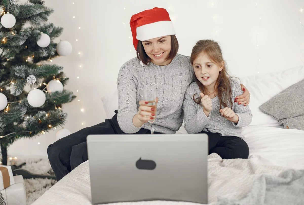 Madre e hija con gorros de Navidad frente a un portátil